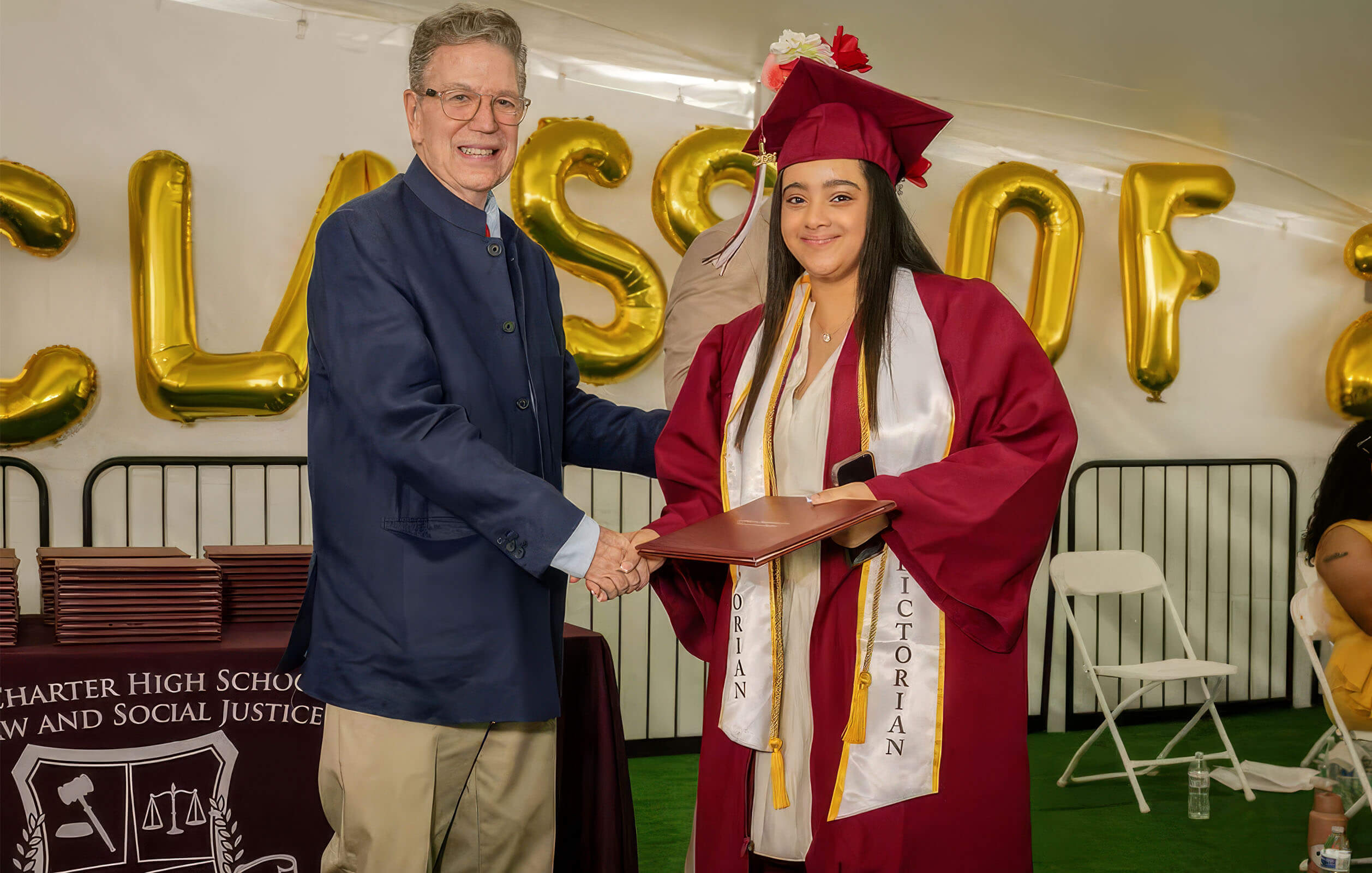 Richard Burke, the founder of the Charter High School for Law and Social Justice, presenting a diploma to a student at graduation