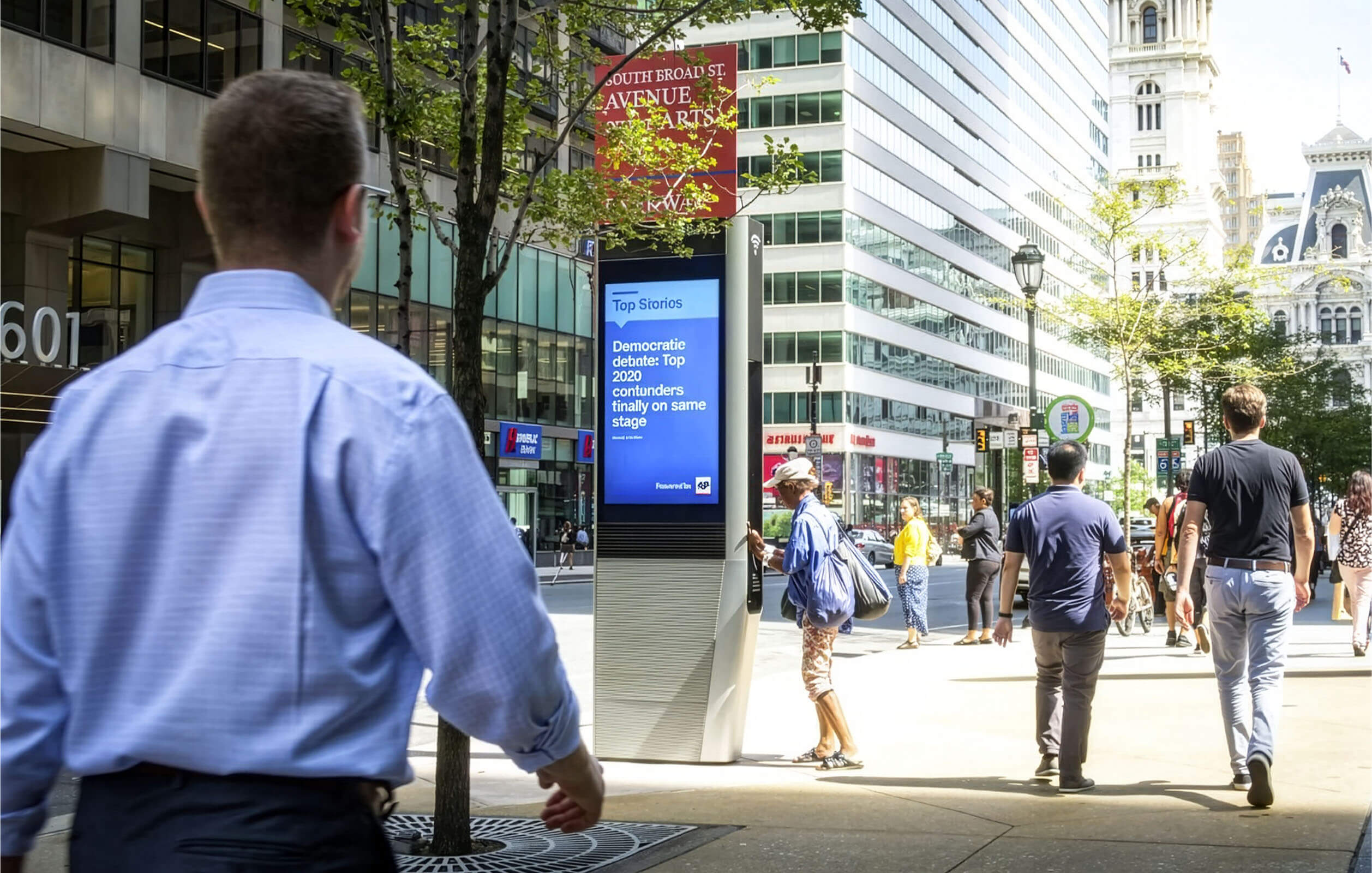 People walking past a LinkNYC kiosk on the streets of New York City