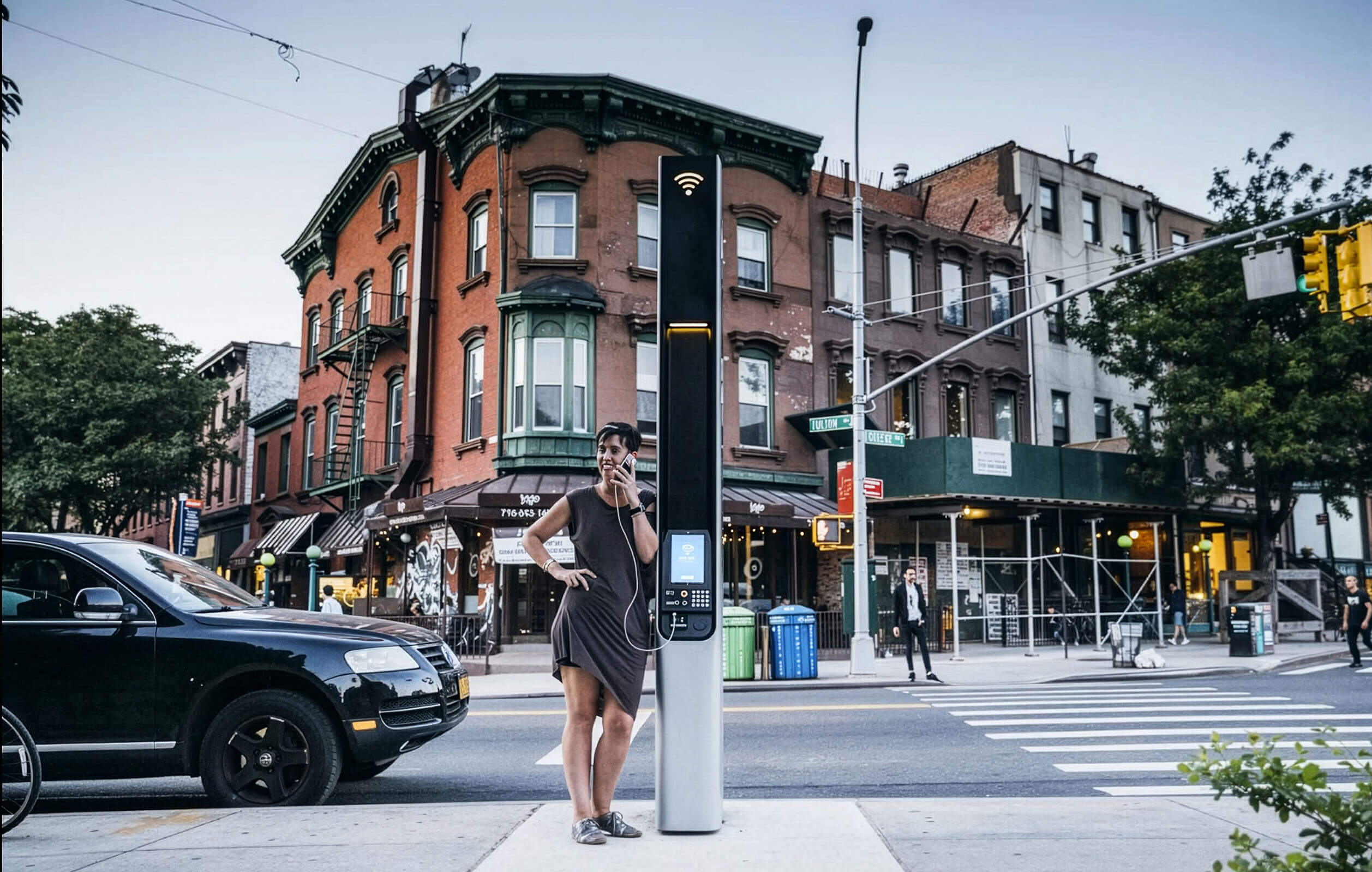 A person standing next to a LinkNYC kiosk, New York City's street-level, high-speed public Wi-Fi network