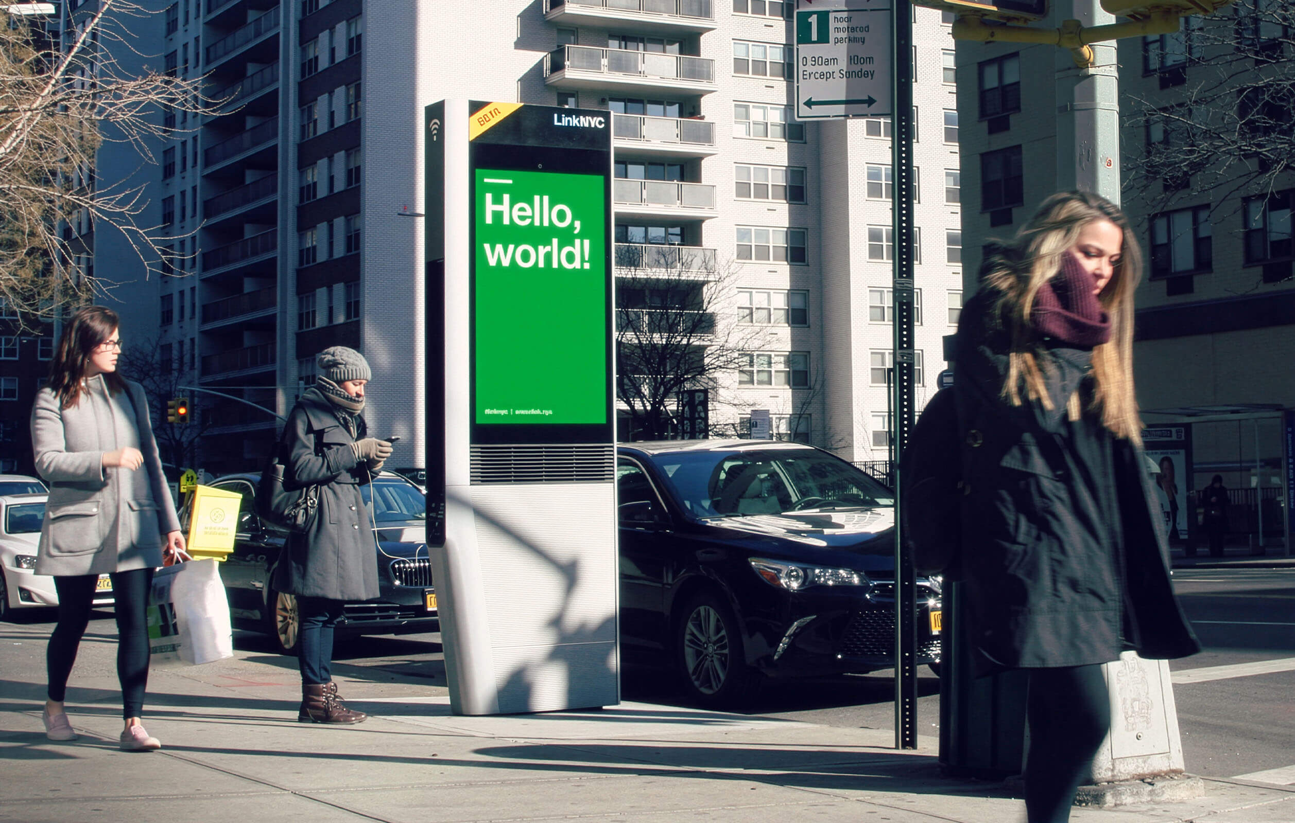 People walking past a LinkNYC kiosk on the streets of New York City in winter