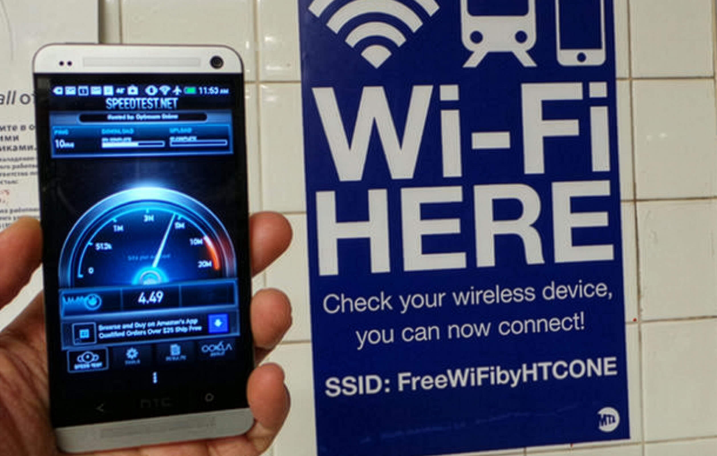 Man holding phone showing Wi-Fi connectivity levels next to signage saying 