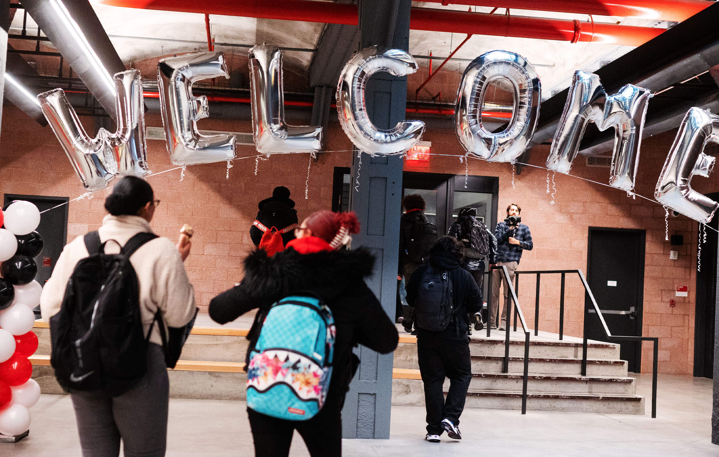 Students walking under a Welcome sign at the grand opening of the DREAM Charter School in the South Bronx